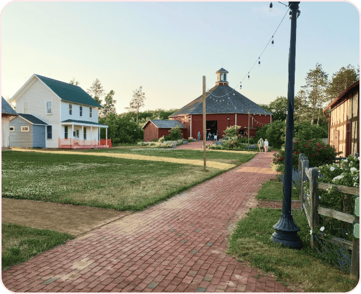 Restored 19th-century farm buildings and a round barn at golden hour